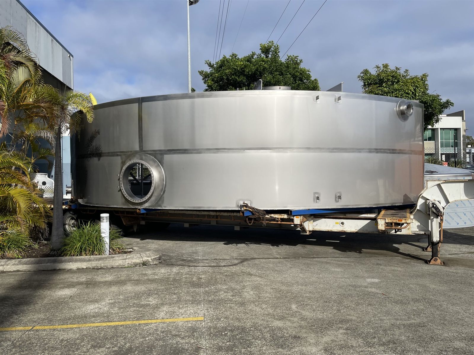 A stainless steel tank section loaded on a trailer outside the workshop