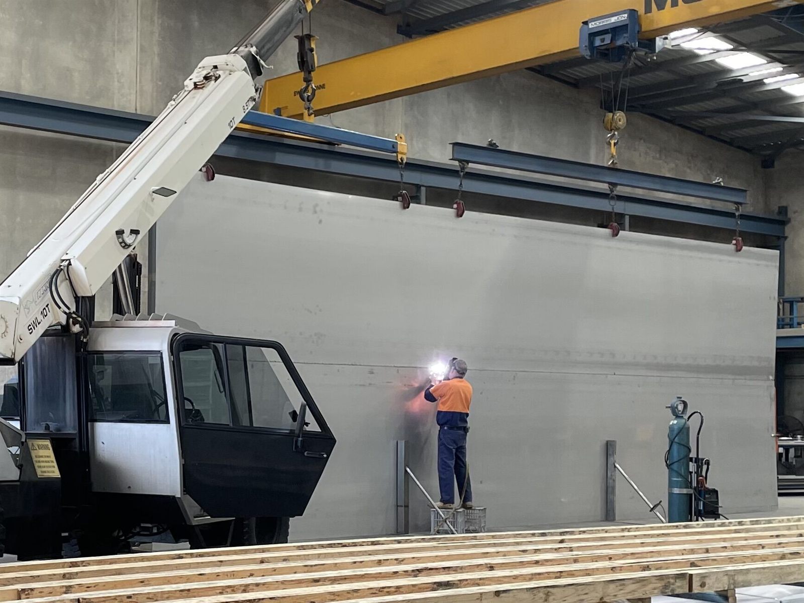 A welder working on a stainless steel tank wall inside the Stainless Tanks Australia workshop